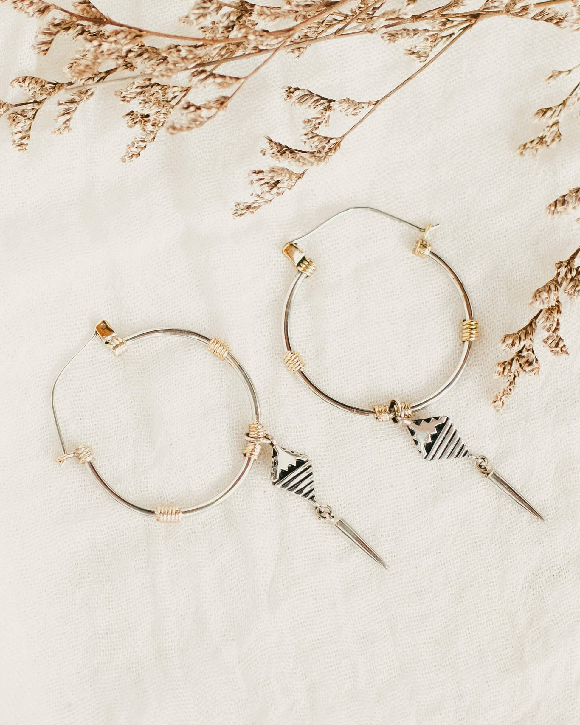 Gold hoop earrings with geometric designs on a light background
