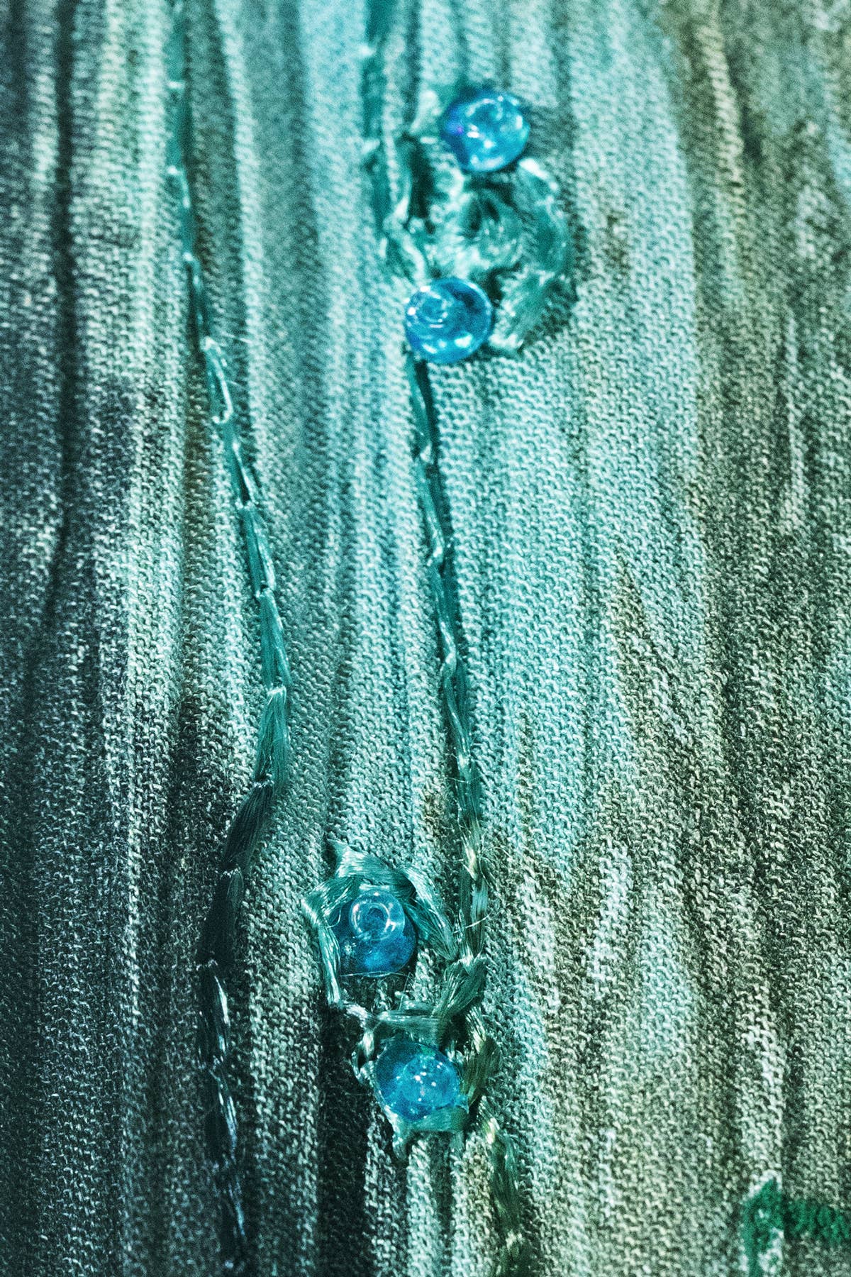 Close-up of a textured green fabric with floral embellishments.
