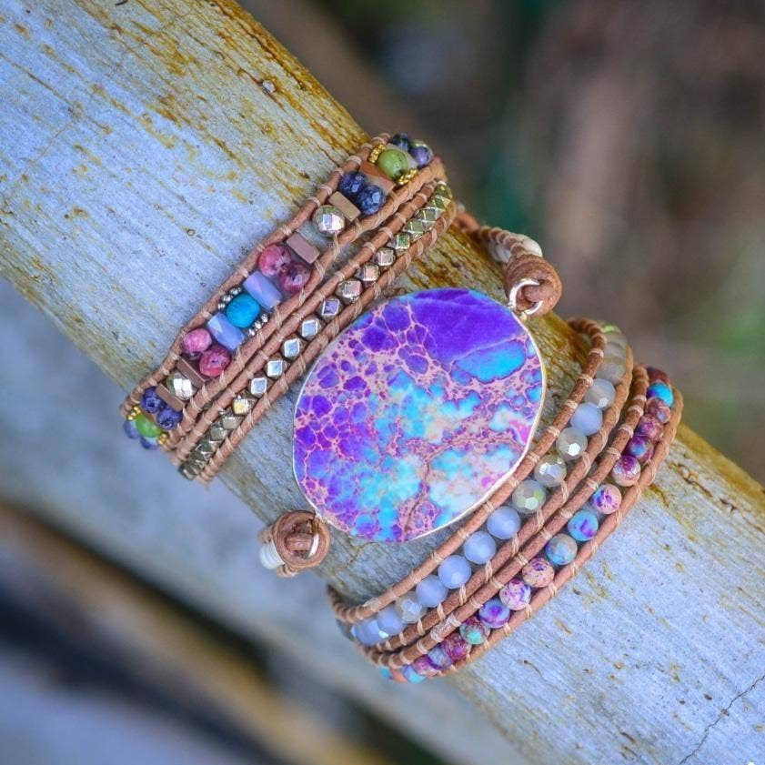 Colorful beaded bracelet with a large purple stone on a wooden surface.