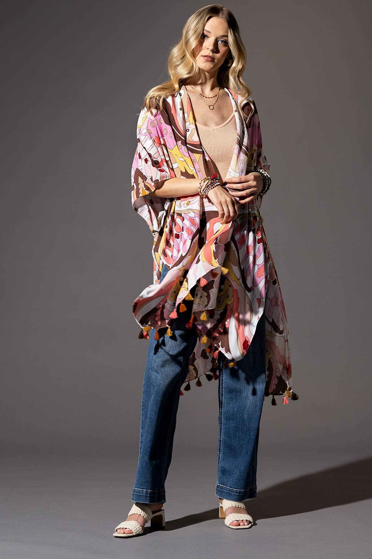 Woman wearing a colorful kimono-style garment against a gray background