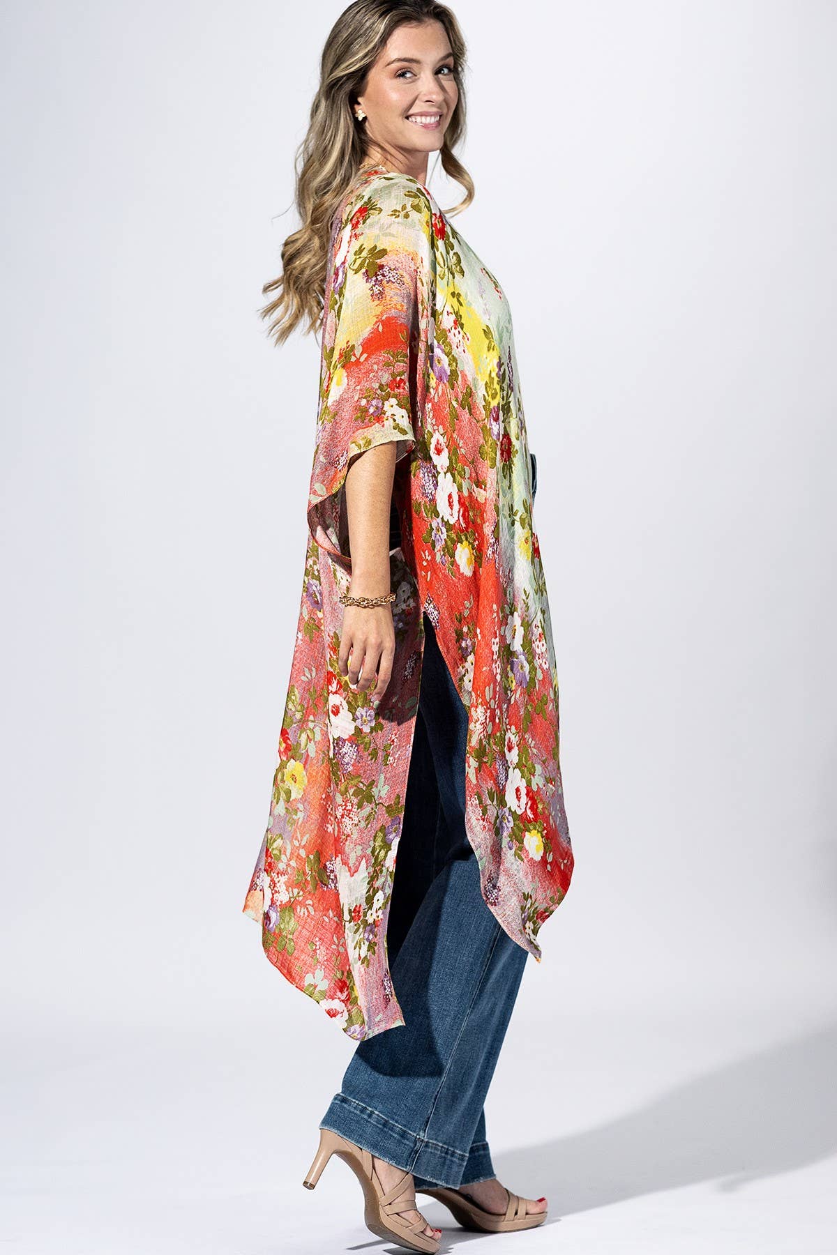 Woman wearing a colorful floral kimono over a dress on a white background